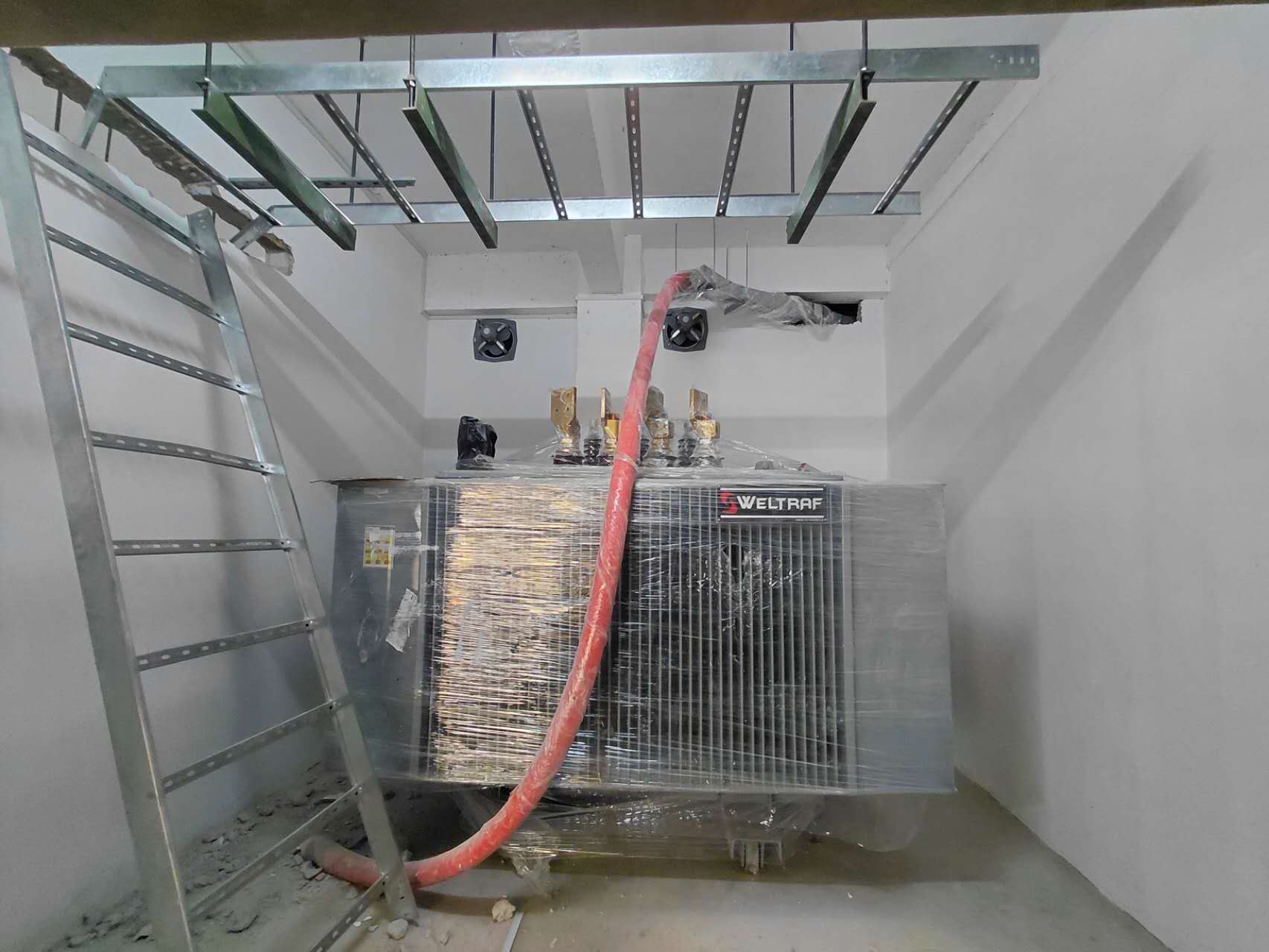 Transformer besar yang diposisikan di dalam ruangan khusus selama proses instalasi
