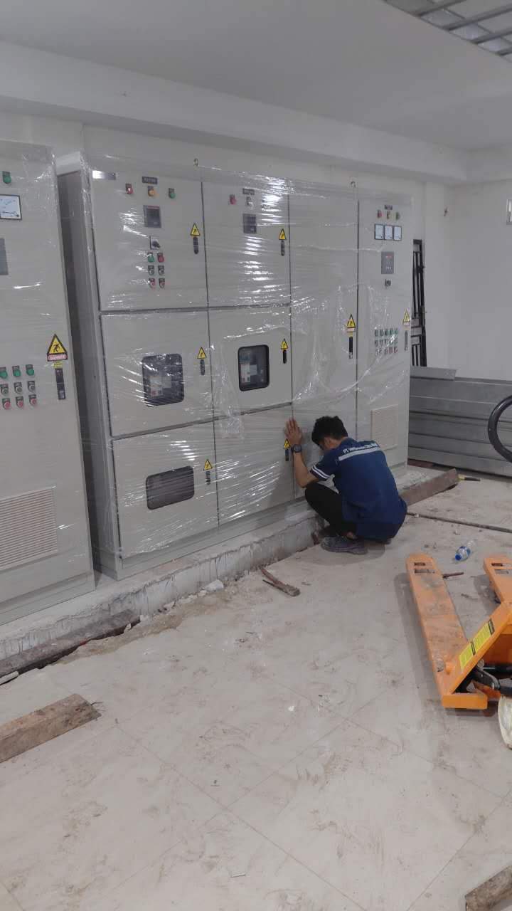 Close-up teknisi mengamankan panel elektrikal pada tempatnya