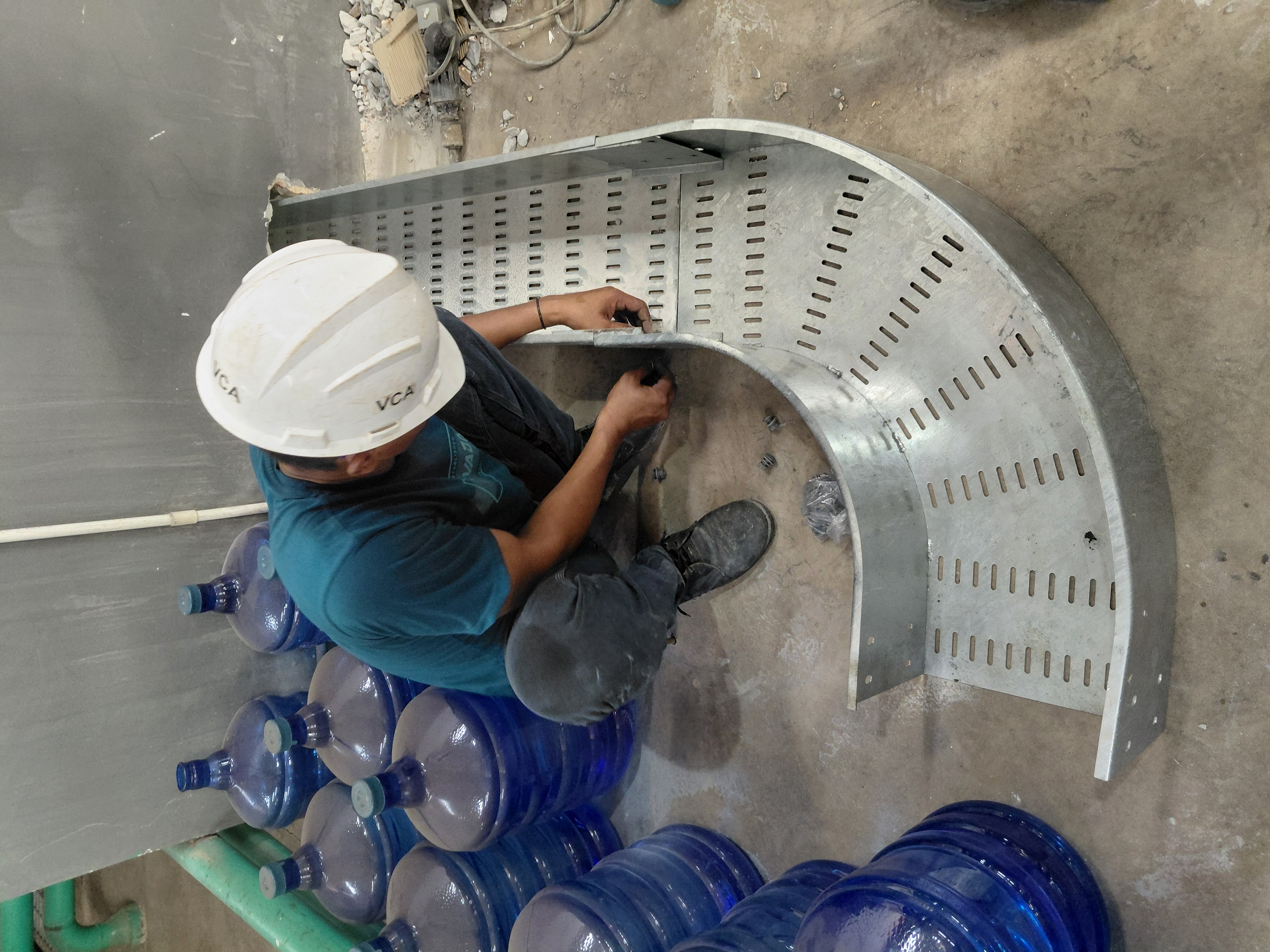 Teknisi mengencangkan bagian-bagian cable tray metal