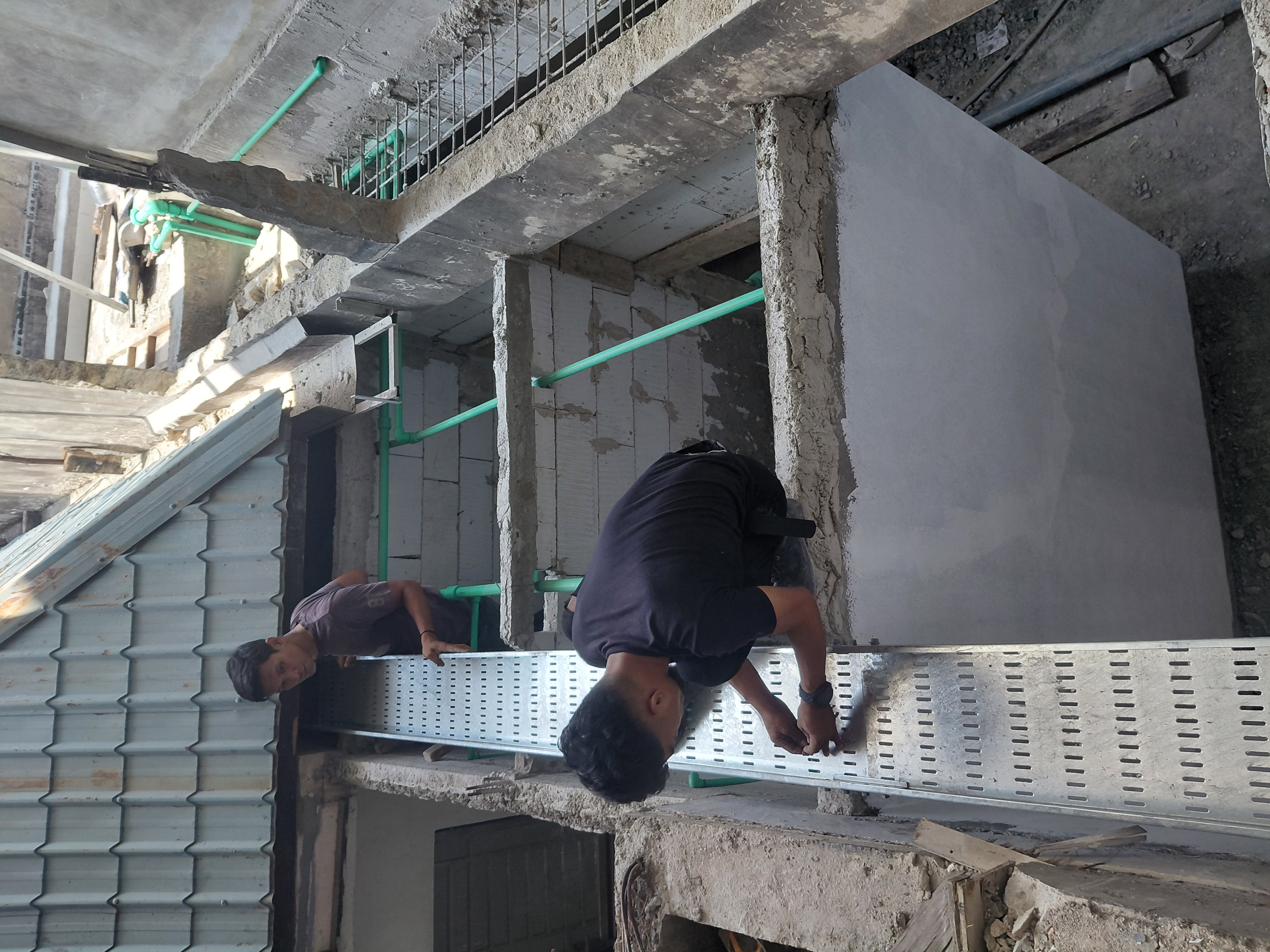 Teknisi memasang cable tray metal melalui area utilitas outdoor